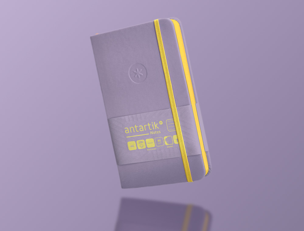 CUADERNO CON GOMILLA ANTARTIK NOTES TAPA DURA A6 HOJAS RAYAS MORADO Y AMARILLO 100 HOJAS 80 GR FSC